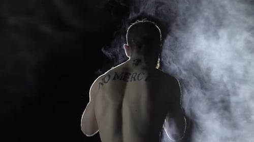 Boxer Does Warmup on Background of Spotlight and Smoke