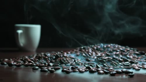 Roasted Coffee Beans Steaming Next to Cup