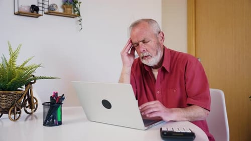 Stressed Senior Man Having Headache Working on Laptop