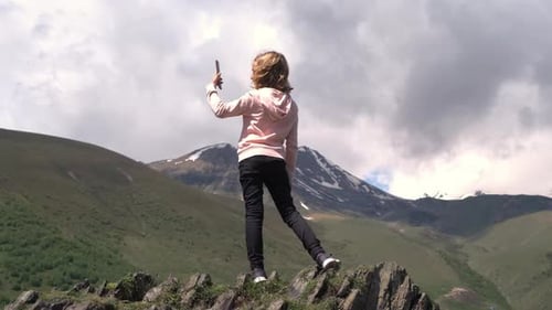 Little Girl Taking Photos While Standing on Rock