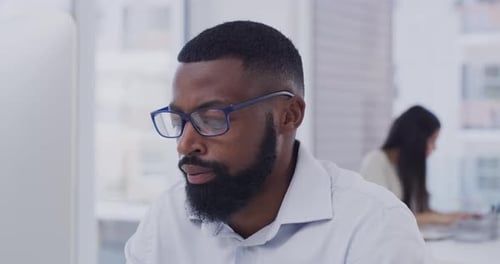 4k video footage of a young businessman sitting at his desk typing in his office