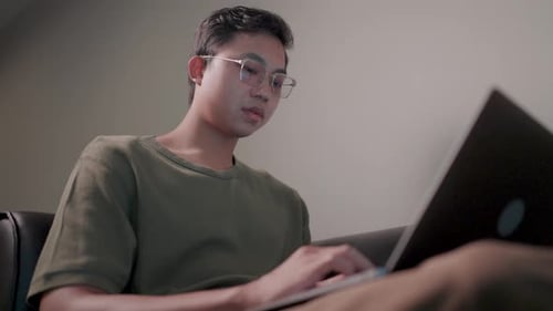 Young Adult Types on Laptop Indoors