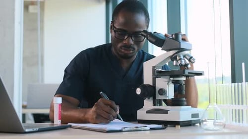 Focused Scientist Examines Specimen With a Microscope