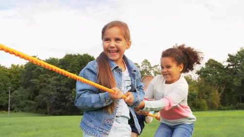 Concepto de infancia, ocio y personas: grupo de niños felices jugando al tira y afloja