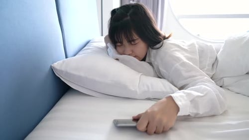 Woman Waking Up in Bed, Reaching for Phone