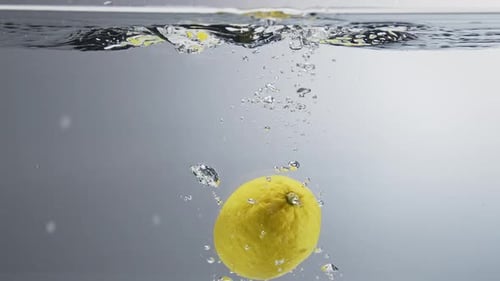 Lemon falling in water. Close up, slow motion