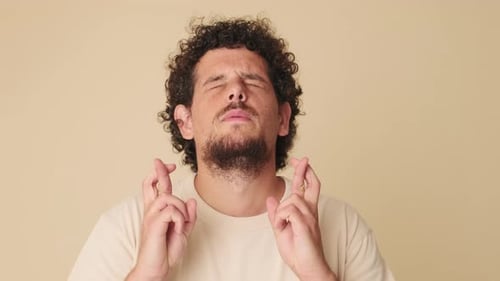 Close up, young man makes wish, isolated on beige background in studio