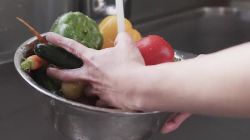 Caucasian male chef washing vegetables in sink in kitchen, slow motion