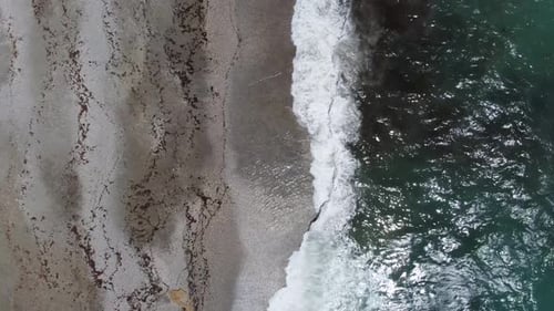 Overlooking the Waves Crashing Against a Wild Rocky Coastline with a View Towards Urban Buildings in