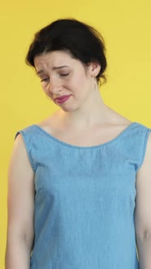 Woman Expressing Sadness Against Yellow Background