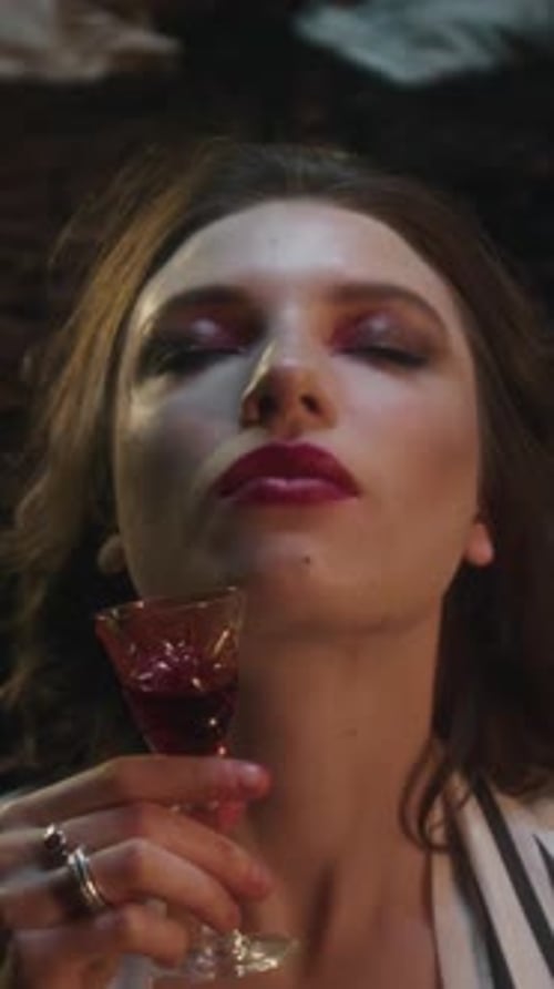 Predatory Vampire Woman Savoring Small Glass of Blood