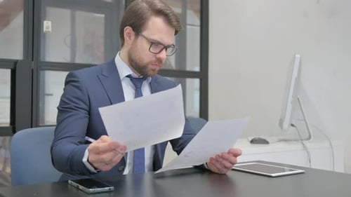 Focused Businessman Reviewing Documents in Office