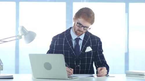Redhead Businessman Writing in Office Documentation