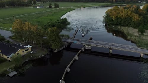 Aerial of Motor boat and two jetskis passing under car bridge during summer