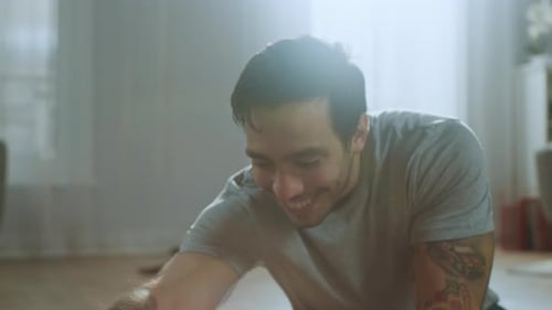 Close Up of a Strong Athletic Fit Man in T-shirt and Shorts Stretches His Body for Morning Exercise