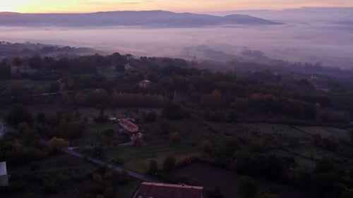 Aerial view of misty sunrise over countryside and mountains, Italy.