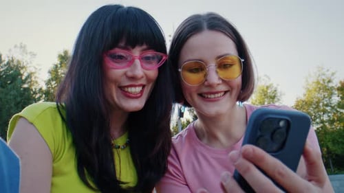 Happy Women Looking at Phone Outdoors in Sunlight