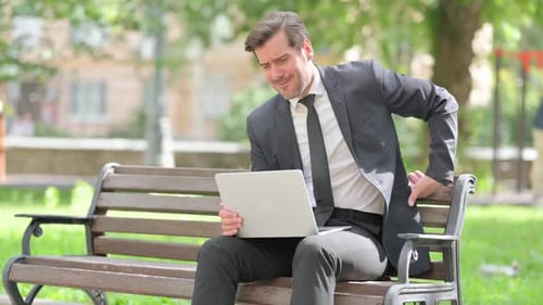 Man Typing on Laptop Experiences Back Pain