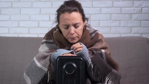Une femme dans un plaid s'allonge sur un radiateur chaud