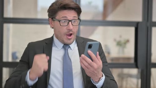 Excited Businessman Celebrates News on Smartphone