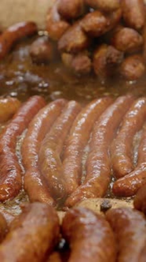 Sausages and Meatballs Cooking on a Flat Surface