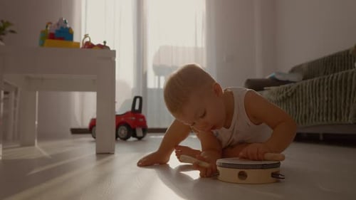 Happy Child Plays Tambourine on Floor