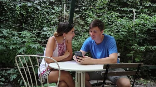 Couple Looking at Phone in Leafy Garden