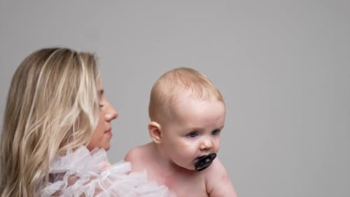 Mother Holds Adorable Baby with Pacifier in Studio
