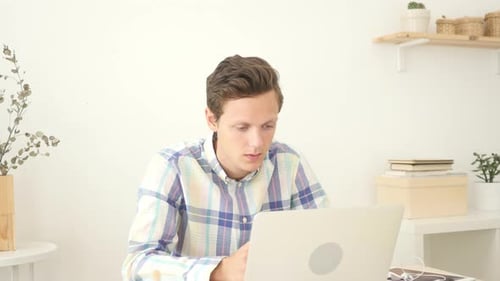 Man Working at Laptop Celebrates Success at Home