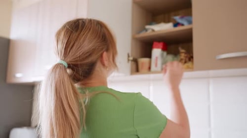 Housewife Retrieving Item From Kitchen Cabinet