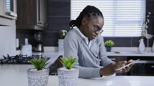 Man Smiling While Using Tablet in Modern Kitchen