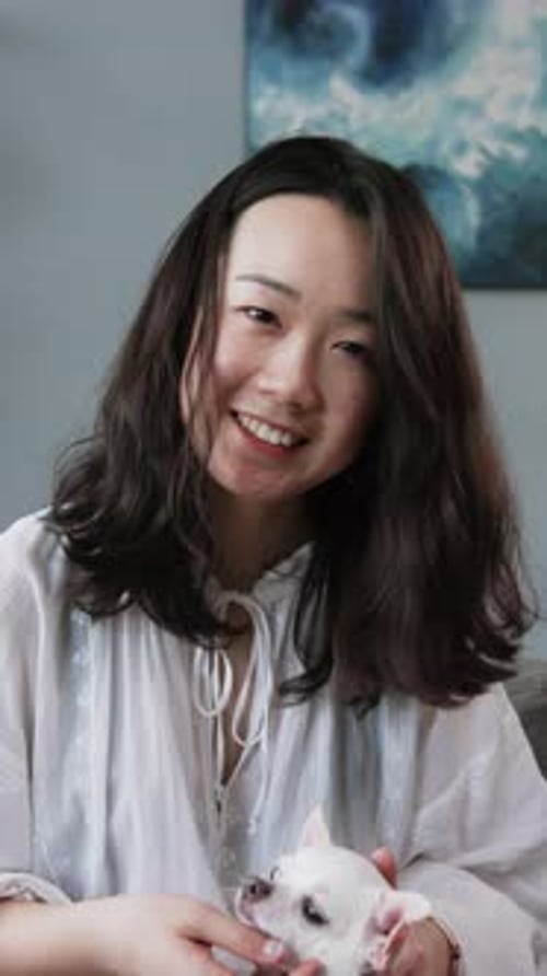 Smiling Woman Sitting with Small Dog in Her Lap