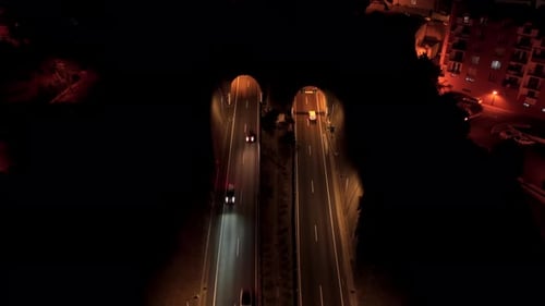 Nachtdrohnenansicht von Autos, die auf einer Stadtautobahn in Portugal in einen Tunnel einfahren