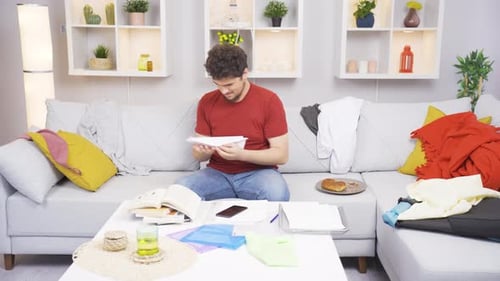 Young Man Folds Paper Airplane in Messy Home