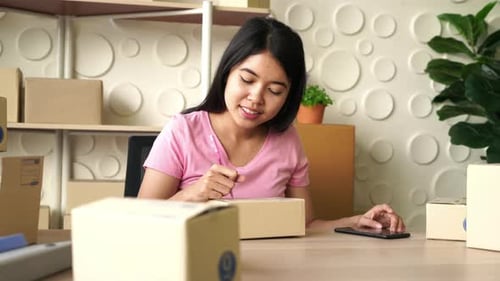Asian Women business owner working at home with packing box on workplace