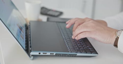 Mann im Hemd tippt auf Laptop-Tastatur im Büro, Nahaufnahme von Händen