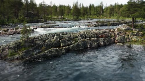 The camera is panning to the right above the wild river. The powerful stream is flowing in the stony