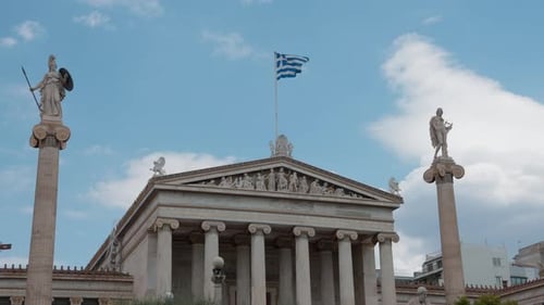 Vue latérale inclinée de l'Académie d'Athènes avec le drapeau grec flottant fièrement dans le vent