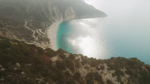 Drone view of misty coastline with winding road and blue sea in Kefalonia Greece