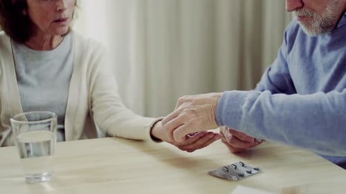Senior Couple Taking Medication at Table Indoors