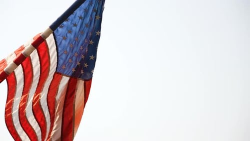 Zeitlupenaufnahme einer amerikanischen Flagge, die im Wind auf einem Fahnenmast weht