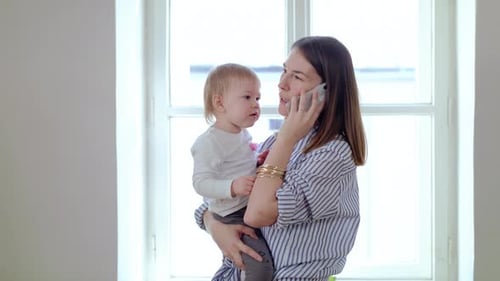 Mother with Small Daughter and Smartphone Working in Home Office Quarantine Concept