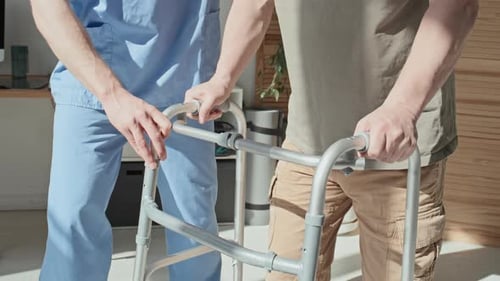 Healthcare Professional Assists Patient with Walker Indoors