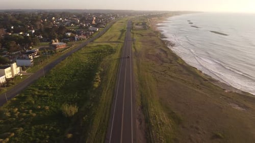 Cinematic Aerial View of a Vehicle Cruising Along the Coastal Road