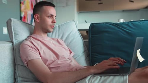 Young Adult Using Laptop on Couch at Home