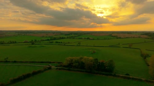 Sonnenuntergang scheint über landwirtschaftlichen Feldern und erzeugt warmes goldenes Licht. Die Abendsonne beleuchtet das Ackerland