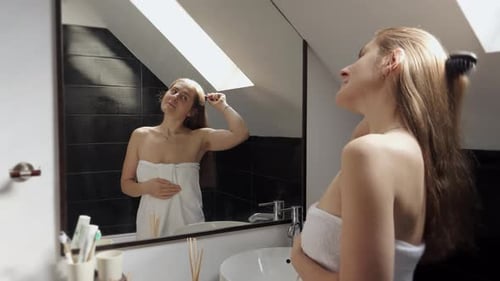 Woman Brushing Hair in Bathroom After Shower