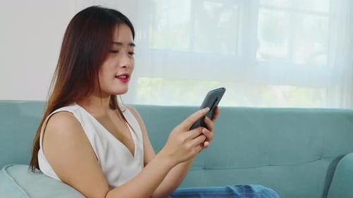 Woman Using Mobile Phone Relaxing on Couch Indoors