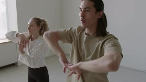 Two Adults Practicing Synchronized Hand Movements in Studio