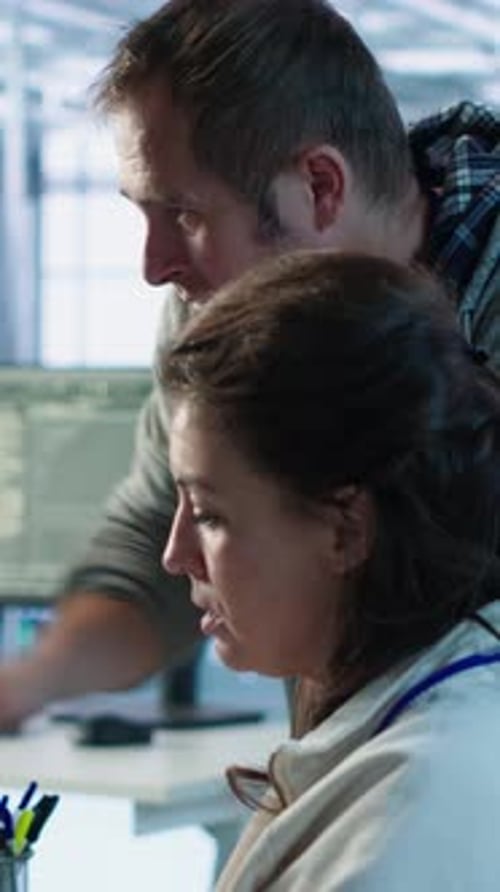 Adults Collaborating at Computer Station in Workplace